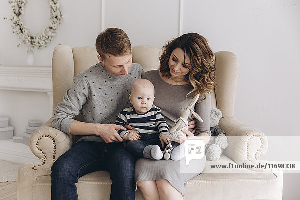 Caucasian mother and father sitting on love seat with baby son