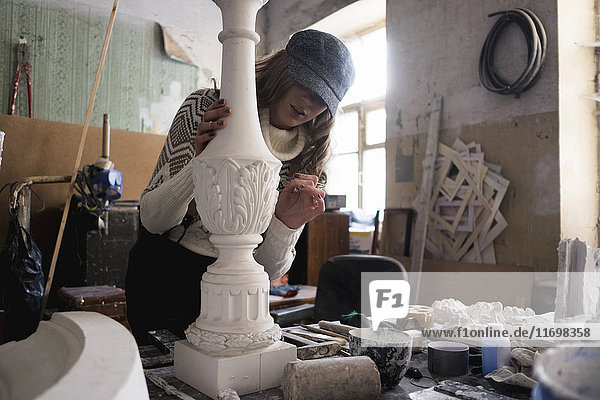 Caucasian sculptor carving plaster piece