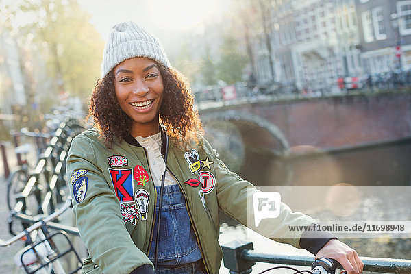 Portrait smiling young woman along urban canal  Amsterdam