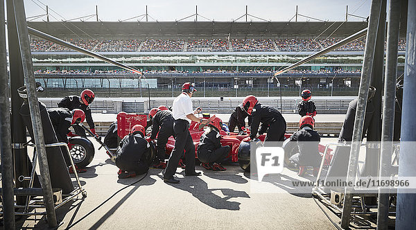 Manager und Boxencrew beim Reifenwechsel auf Formel 1-Rennwagen in der Boxengasse
