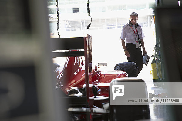 Manager examining formula one race car in repair garage