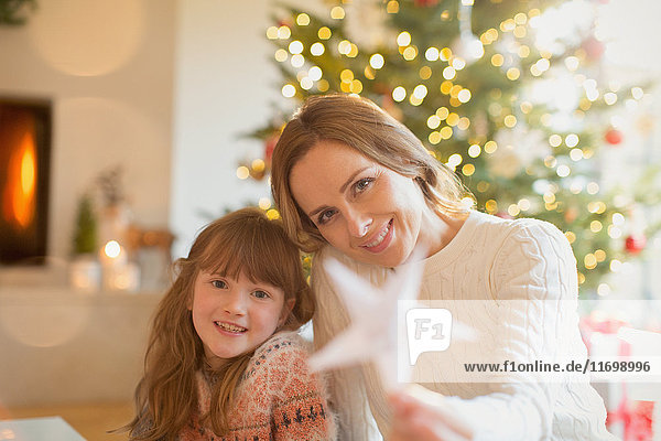 Portrait lächelnde Mutter und Tochter mit Weihnachtsstern