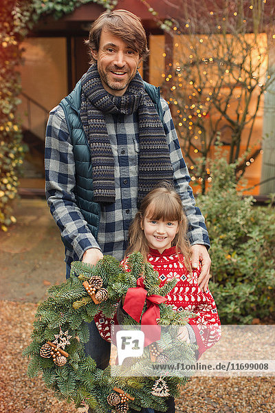 Portrait lächelnder Vater und Tochter mit Weihnachtskranz