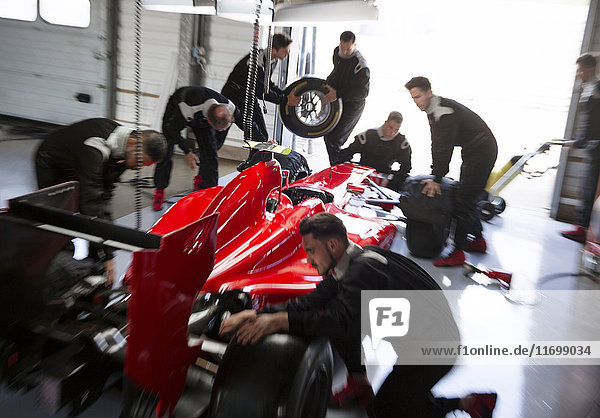 Pit crew working on formula one race car in repair garage