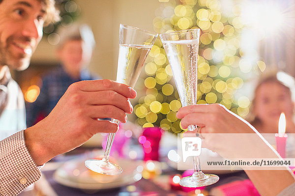 Ehepaar stößt beim Weihnachtsessen mit Champagnerflöten an