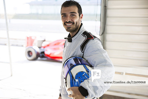 Porträt souveräner Formel-1-Rennwagenfahrer mit Helm in der Reparaturwerkstatt