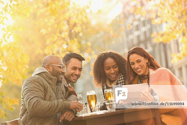 Lächelnde Freunde trinken Bier und nehmen Selfie mit Digital Tablet im Herbst Bürgersteig Cafe