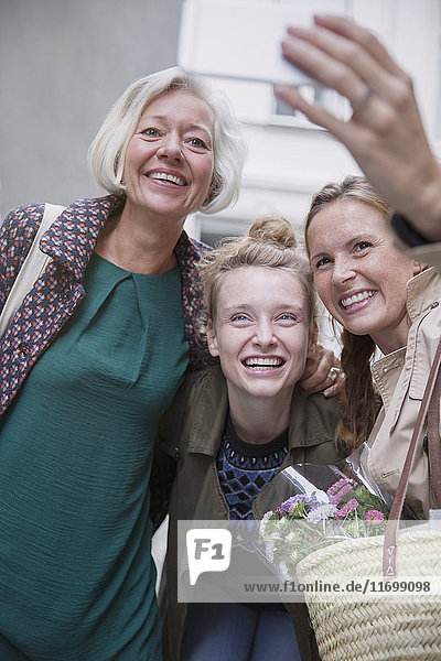 Smiling mother and daughters taking selfie with camera phone