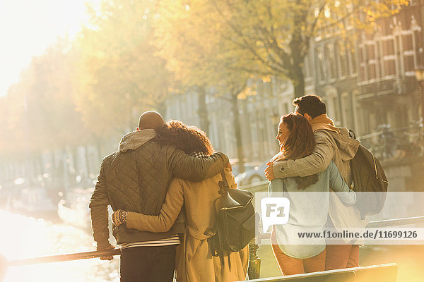 Young couples hugging on bridge over sunny autumn canal  Amsterdam