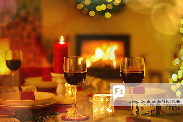 Red wine and candles on ambient Christmas table in front of fireplace
