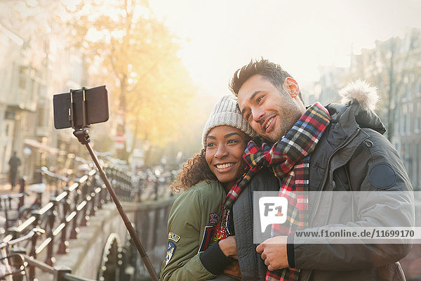 Zärtliche Paarumarmung und Selfie mit Selfie-Stick auf der Herbstbrücke  Amsterdam