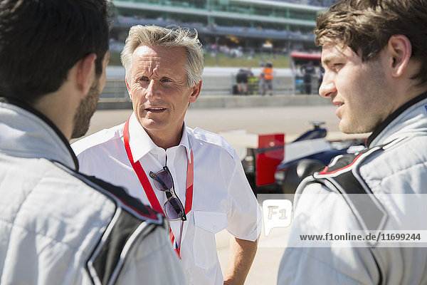Manager talking to formula one drivers on sports track
