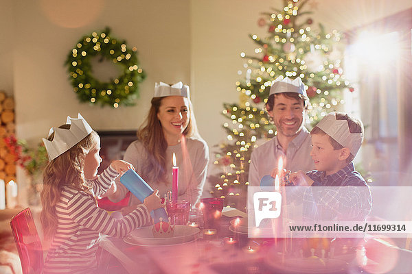 Family wearing paper crowns at Christmas dinner table