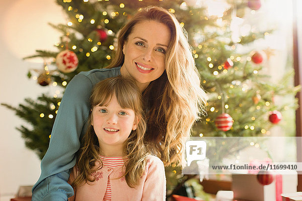 Porträt lächelnde Mutter und Tochter vor dem Weihnachtsbaum