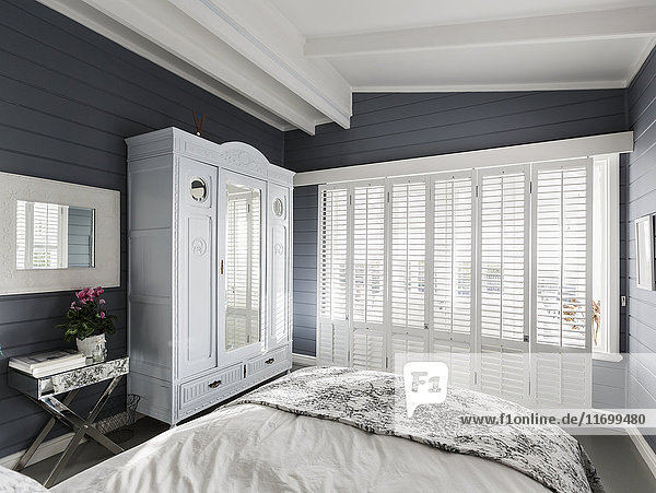 Luxuriöses Musterschlafzimmer mit weißen Fensterläden und Gewölbedecke