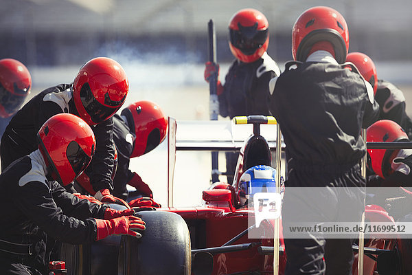 Pit crew replacing tires on formula one race car in pit lane