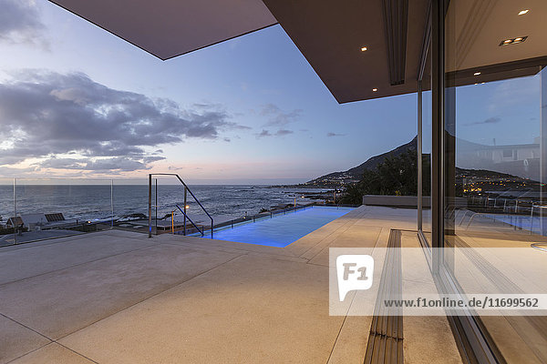 Terrasse mit Swimmingpool und Meerblick in der Abenddämmerung