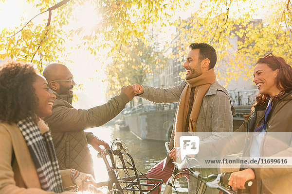 Friends greeting with fist bump along autumn canal