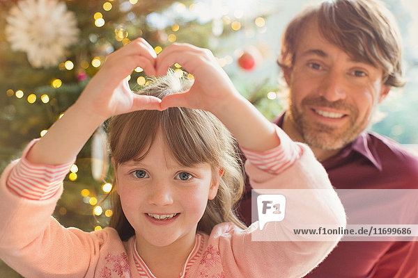 Porträt lächelnd Vater und Tochter bilden Herz-Form in der Nähe von Weihnachtsbaum