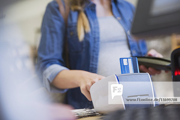 Female shopper using credit card reader in shop