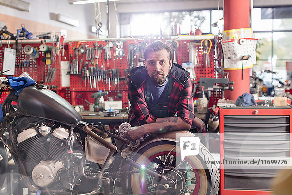 Porträt seriöser  selbstbewusster Motorradmechaniker in der Werkstatt