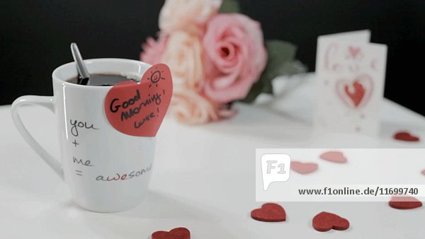 Kaffeetasse mit herzförmigem Aufkleber  Herzen und Blumen auf dem Tisch