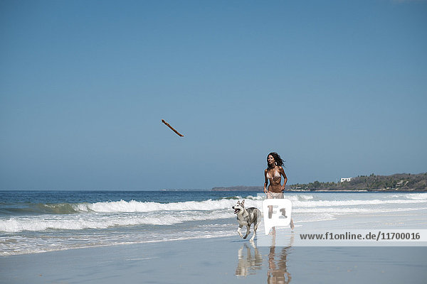 Mexico  Riviera Nayarit beach  young woman running with husky dog