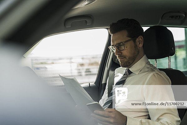 Successful businessman sitting in car reading files
