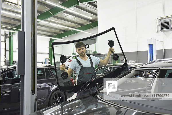 Car mechanic in a workshop changing car window