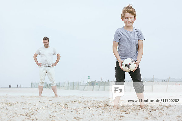 Portrait of smiling little boy playing with his father on the beach