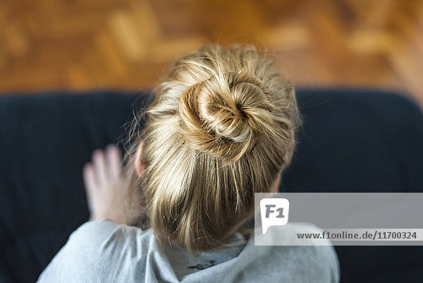 Woman with ginger hair bun sitting on sofa