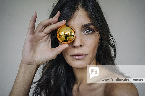 Portrait of attractive dark-haired young woman holding Christmas bauble
