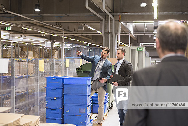 Three businessmen in factory warehouse