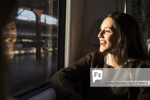 Happy young woman on a train looking out of window