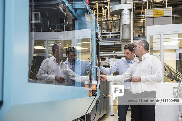Two men looking at machine in factory shop floor
