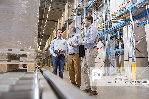 Three men talking in factory warehouse