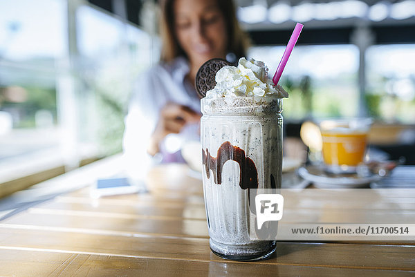 Glass of chocolate milkshake with cream on table