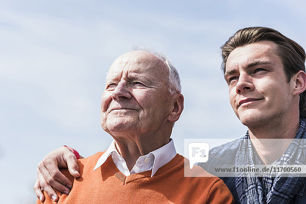 Lächelnder älterer Mann und erwachsener Enkel im Freien