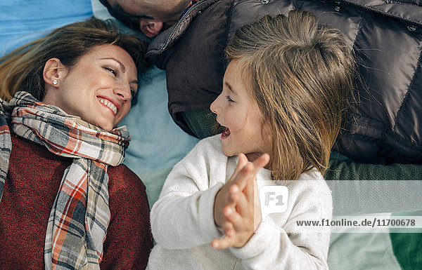 Glückliches Mädchen mit ihrer Familie auf der Decke klatschende Hände