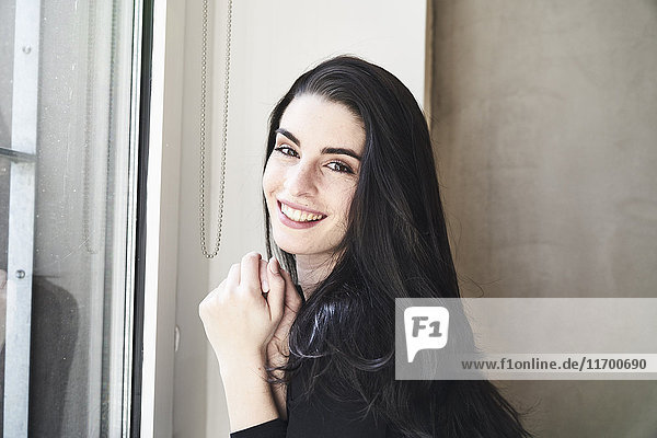 Porträt einer lächelnden jungen Frau am Fenster