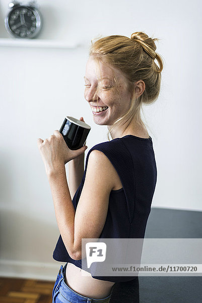 Young woman standing in kitchen  drinking coffee