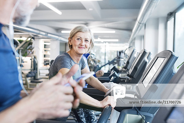 Gruppe von fit Senioren auf Laufbändern im Fitnessstudio  Frau lächelnd