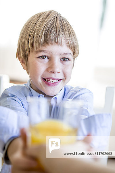Lächelnder Junge mit einem Glas Orangensaft
