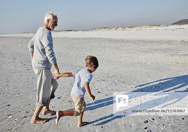 Grandfather and grandson strolling on the beach