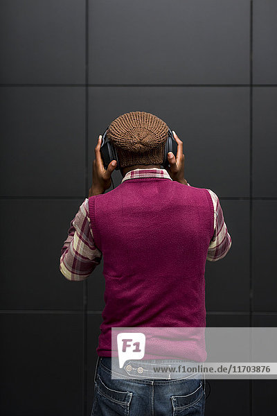 Rückansicht des Mannes beim Musikhören mit Kopfhörer und Handy