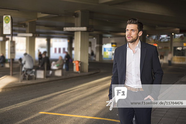 Portrait of young businessman waiting at bus terminal