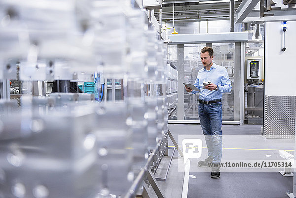 Man with tablet in factory shop floor examining products