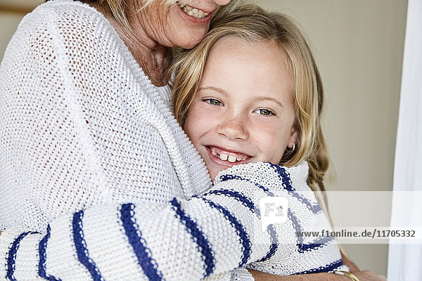 Porträt eines glücklichen kleinen Mädchens  das seine Großmutter umarmt.