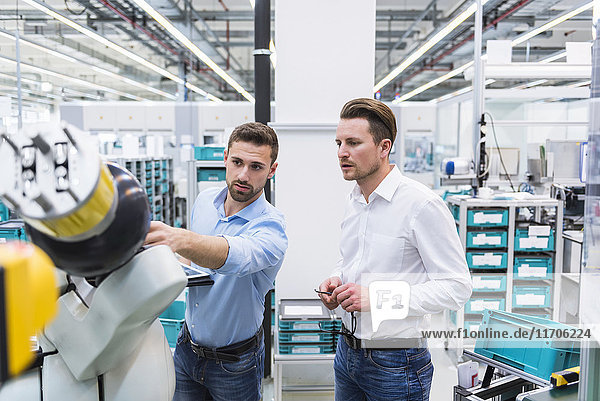 Zwei Männer mit Tablettenprüfroboter in der Fabrikhalle
