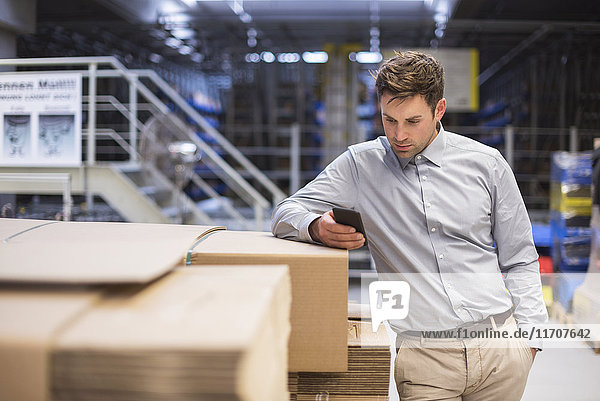 Man in factory looking at cell phone